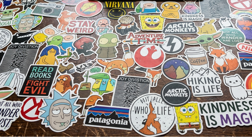 Collection of various stickers on a desk with a laptop and coffee mug in the background